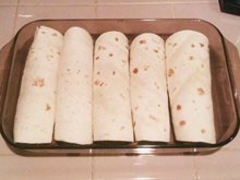Burritos ready to be covered with the enchilada sauce from the crockpot.