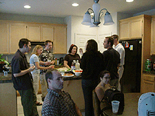 Dave, Natalie and Peter talk while people enjoy snacks in the kitchen...